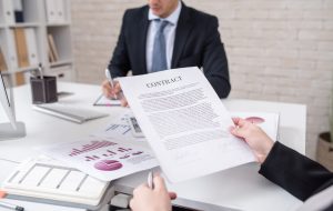 Closeup of unrecognizable business person holding contract and reading it during negotiations meeting with partner, copy space